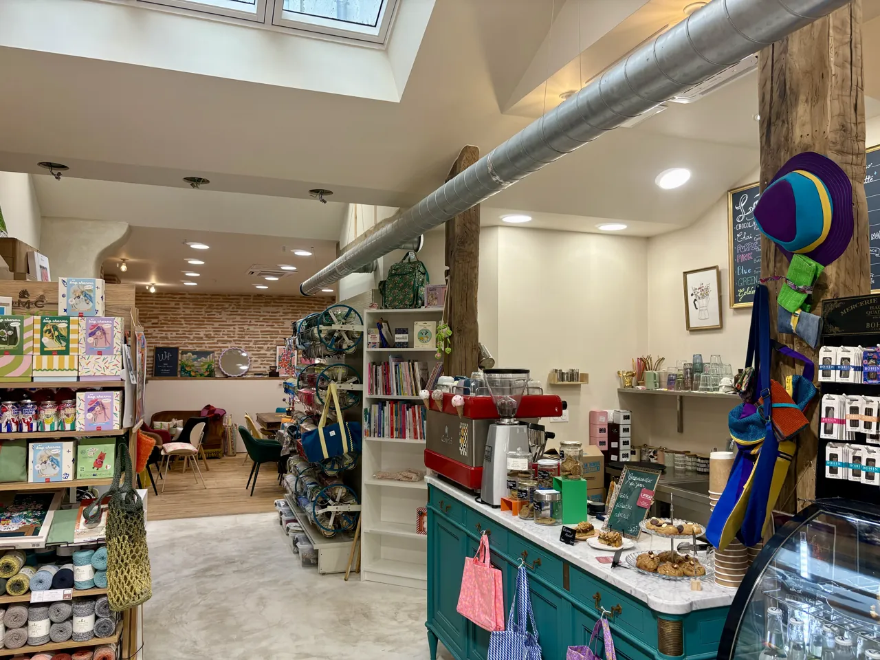 L’intérieur de Moha à Lavaur : le comptoir turquoise avec sa machine à espresso et ses pâtisseries, les rayons de mercerie et le coin salon